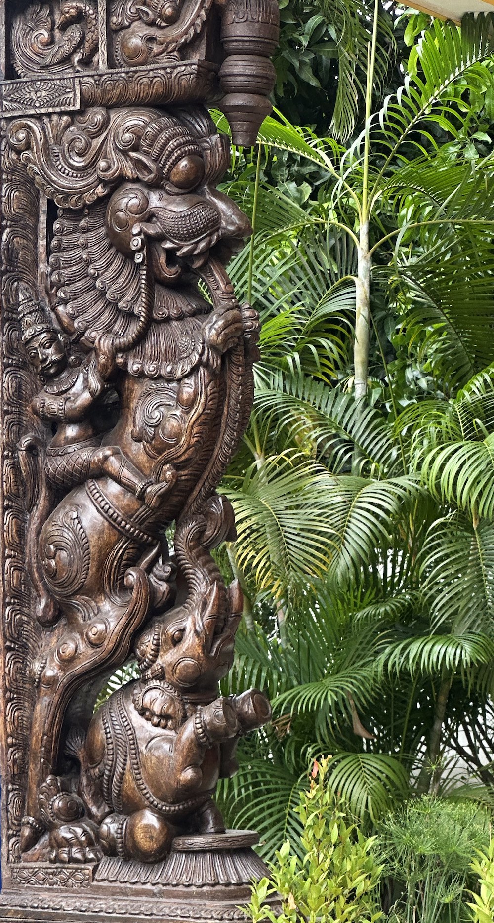 Carved wooden temple pillar, greenery